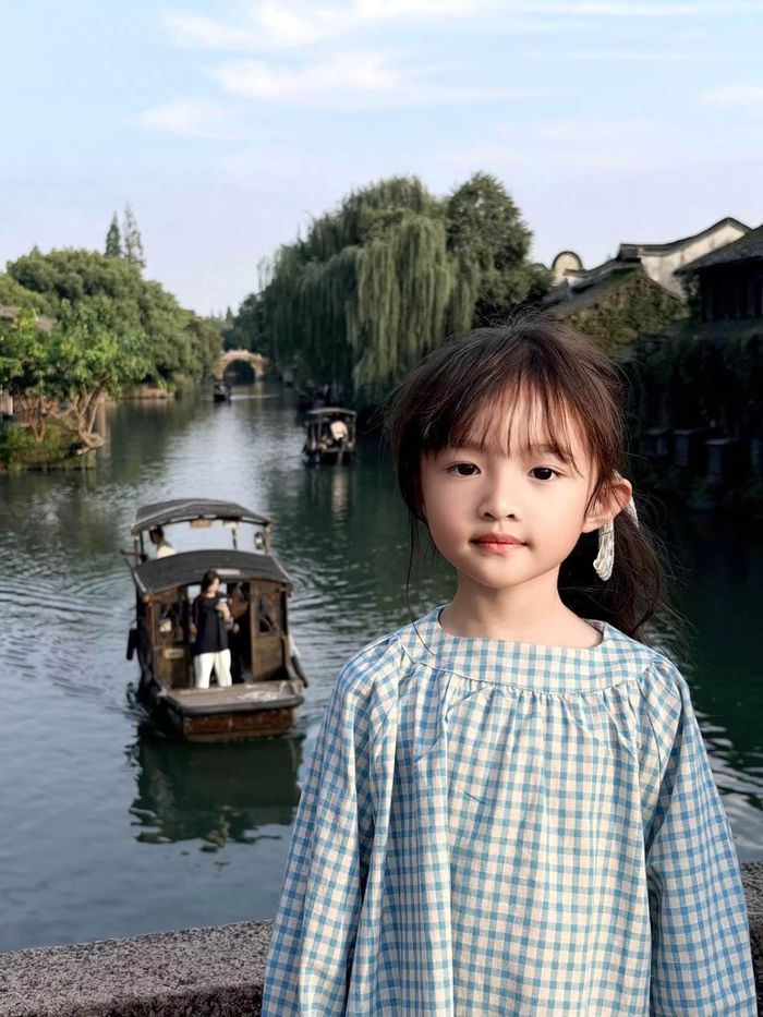 Đặc biệt, bé Winnie - hình ảnh con gái lớn nhà cặp đôi, tạo dáng tự nhiên trong chiếc váy kẻ caro xanh trắng khi dạo chơi ở Ô Trấn khiến fan không khỏi trầm trồ.