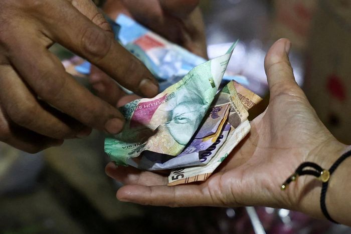 Người bán hàng và khách trao đổi tiền giấy rupiah Indonesia.