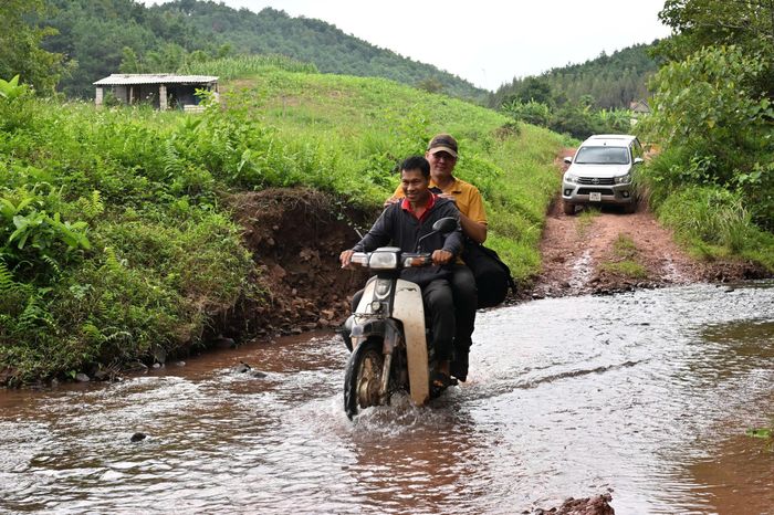  Trên đường vào điểm thi công có nhiều đoạn đường đất bị suối cắt ngang, gây khó khăn cho việc di chuyển. Người dân địa phương dùng xe máy hỗ trợ đưa cán bộ, kỹ thuật viên Viettel vượt đoạn ngập để vào tới bản. 