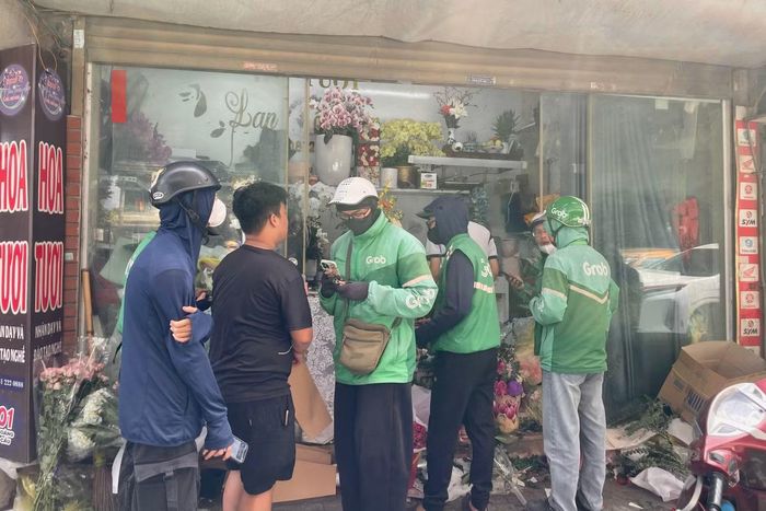 Shipper chờ nhận hoa trước một cửa hàng hoa trên phố Hoàng Cầu.
