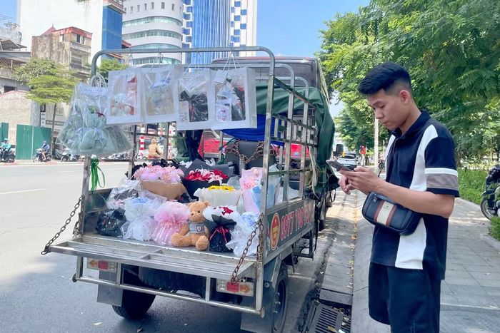 Anh Tuấn (Bắc Ninh) thuê xe ba bánh chở hoa và đồ lưu niệm đến cổng trường học bán ngày 20/10. Anh cho biết khách hàng chủ yếu là sinh viên nên sản phẩm có giá 50.000-200.000 đồng, dự kiến bán hết trong ngày.