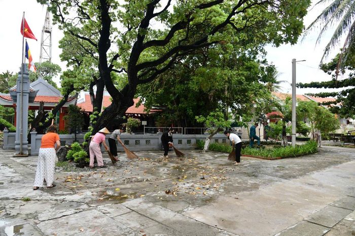 Phụ nữ đảo Sinh Tồn quét dọn vệ sinh khu dân cư.