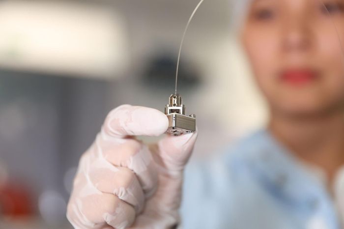 TS Âu Thị Hường, Giám đốc phụ trách sản xuất nguồn bán dẫn tại Quandela đang cầm trên tay một trong những linh kiện quan trọng nhất - "trái tim" của chiếc máy tính lượng tử: một nguồn phát photon đơn dựa trên chấm lượng tử (quantum dot) được kết nối với sợi quang, có nhiệm vụ truyền các photon vào bộ phận chính của máy tính thông qua mạng lưới các ống dẫn sóng và sợi quang. Ảnh: Quandela