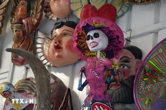 Một mô hình Catrina-người phụ nữ với chiếc mũ rộng vành, váy áo lộng lẫy và gương mặt hóa trang thành hộp sọ trong một quầy bánh Pan de muerto tại thủ đô Mexico City, Mexico. (Ảnh: Phi Hùng/TTXVN)