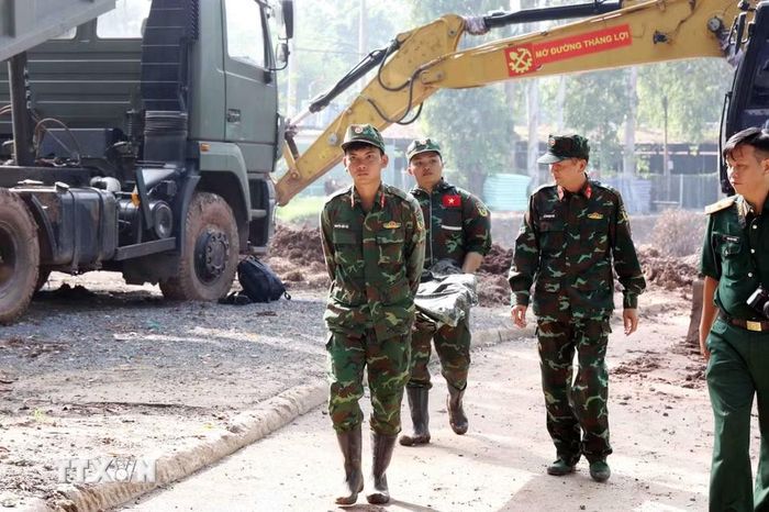 Chiến sỹ đội K74 đưa di cốt liệt sỹ từ hố khai quật tới phòng lấy mẫu, lưu mẫu xác định danh tính liệt sỹ. (Ảnh: Xuân Khu/TTXVN)