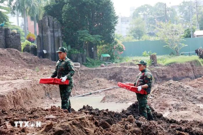 Chiến sỹ đội K74 đưa di cốt liệt sỹ từ hố khai quật tới phòng lấy mẫu, lưu mẫu xác định danh tính liệt sỹ. (Ảnh: Xuân Khu/TTXVN)