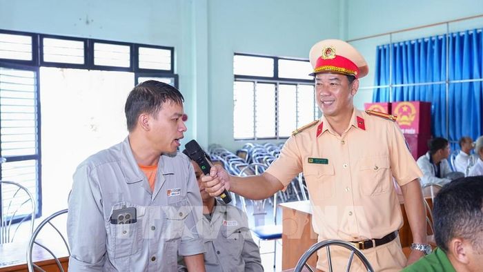 Trung tá Cao Thanh Vũ, cán bộ Phòng CSGT Công an tỉnh Tây Ninh trao đổi, hướng dẫn người dân các kiến thức cần thiết khi điều khiển xe mô tô, xe gắn máy, chủ động phòng ngừa nguy cơ tai nạn giao thông. Ảnh: Minh Phú - TTXVN