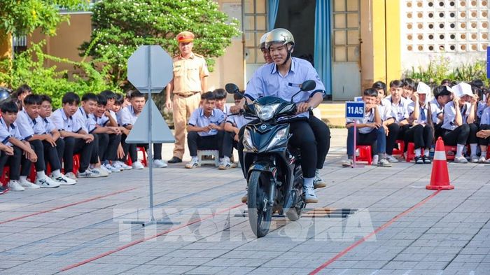 Học sinh Trường Trung học phổ thông Hoàng Văn Thụ, xã Châu Thành, tỉnh Tây Ninh theo dõi phần thực hành kỹ năng lái xe mô tô an toàn trên sa hình. Ảnh: Minh Phú - TTXVN