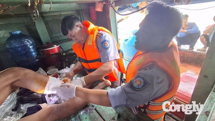 Lực lượng chức năng Bộ Tư lệnh Vùng Cảnh sát biển 4 tiến hành băng bó vết thương, cầm máu tạm thời cho ngư dân gặp nạn trên biển.