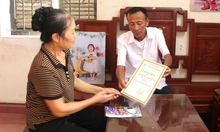  Nghệ nhân Nguyễn Thị Huệ cùng chồng xem lại giấy chứng nhận giải Nhất Hội thi hát đối đáp quan họ đầu xuân năm 2015. 