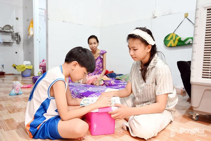 Vừa học xong lớp 3, bé Ngọc Anh (11 tuổi) xếp lại sách vở để ở nhà túc trực bên giường bệnh; còn Ngọc Sơn (9 tuổi) cũng đứng trước nguy cơ phải nghỉ học vì gia cảnh nghèo khó. Ảnh: Thu Hiền