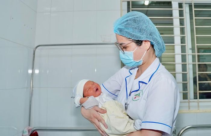 Khoảnh khắc thiêng liêng sau đêm trắng: Nữ hộ sinh bế trên tay em bé vừa cất tiếng khóc chào đời. Giữa những căng thẳng của “lằn ranh” sinh tử, một sự sống mới đã bắt đầu.
