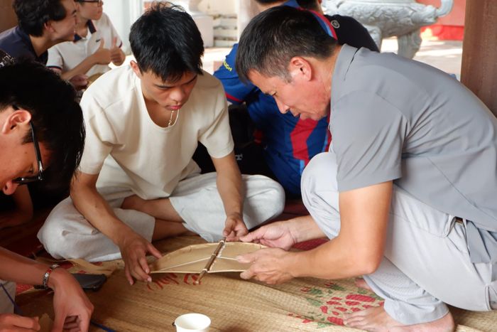 Nghệ nhân Nguyễn Văn Quyết tỉ mỉ hướng dẫn từng công đoạn cho các bạn trẻ. (Ảnh: Hương Giang)