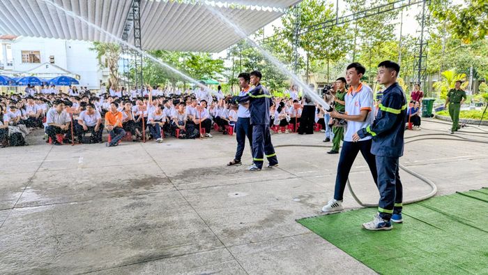 Các em học sinh lần đầu tiên cầm vòi nước, thực hành phun nước tiêu điểm. Ảnh: Nghiêm Túc