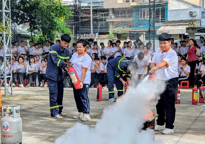 Các em học sinh trực tiếp được cán, bộ chiến sĩ PCCC hướng dẫn sử dụng bình chữa cháy dập lửa. Ảnh: Nghiêm Túc