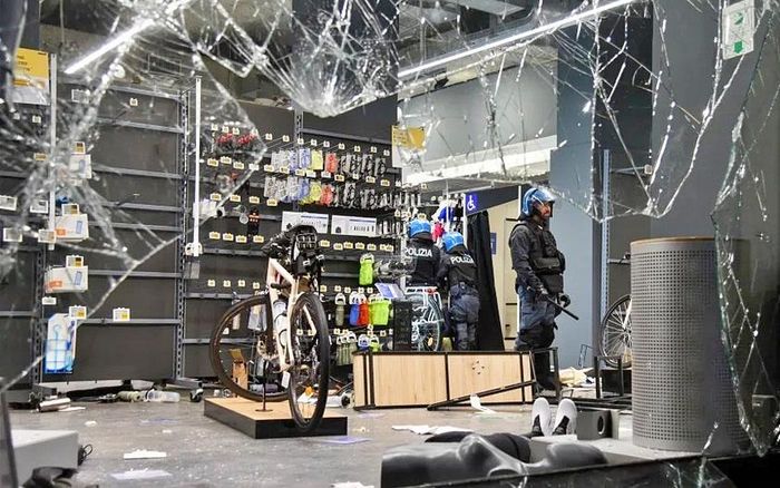 Cảnh sát Italy làm nhiệm vụ ngày 18/10, tại cửa hàng bán đồ thể thao Decathlon bị cướp phá ở Milan. Ảnh: Stringer/Reuters
