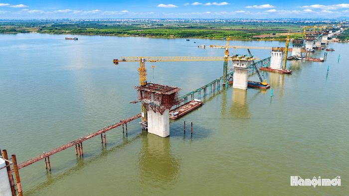 Khu vực cầu chính vượt sông Hồng đang triển khai công nghệ đúc hẫng cân bằng. Thay vì lắp ghép các phiến dầm hoàn chỉnh như tại cầu cạn, nhà thầu thi công từng đốt dầm bê tông cốt thép dự ứng lực nối tiếp từ trụ, vươn dần về hai phía. Các đốt dầm được liên kết bằng hệ thống cốt thép và cáp dự ứng lực, tạo thành kết cấu có khả năng chịu lực lớn, phù hợp với những nhịp cầu vượt sông có khẩu độ lớn.