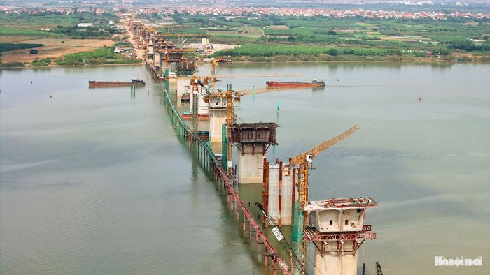 Trên mặt sông, các nhà thầu đang triển khai đúc hẫng những nhịp chính vượt sông Hồng. Từng đốt dầm được thi công nối tiếp từ trụ, vươn dần về hai phía, tạo nên những cánh tay bê tông lớn giữa không gian sông nước.