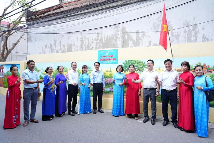 Các đại biểu thực hiện gắn biển công trình “Tuyến đường bích họa” tại thôn Hạ. Ảnh: Nguyễn Sơn