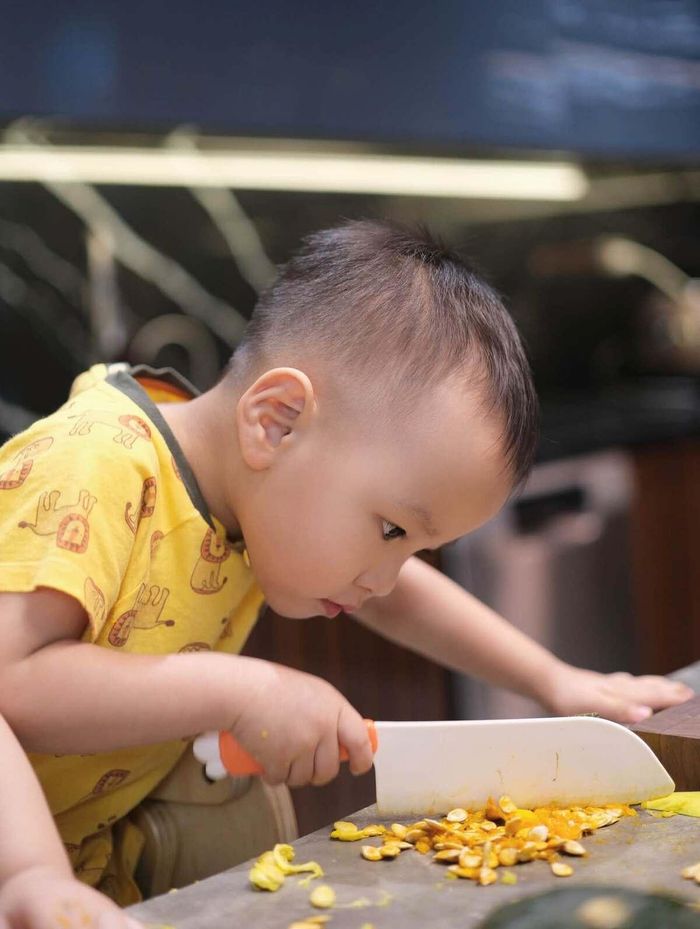 Cậu nhóc Jimmy tỏ ra chăm chút với đám ruột bí đỏ khi làm theo những động tác băm, thái của mẹ bằng dao nhựa.