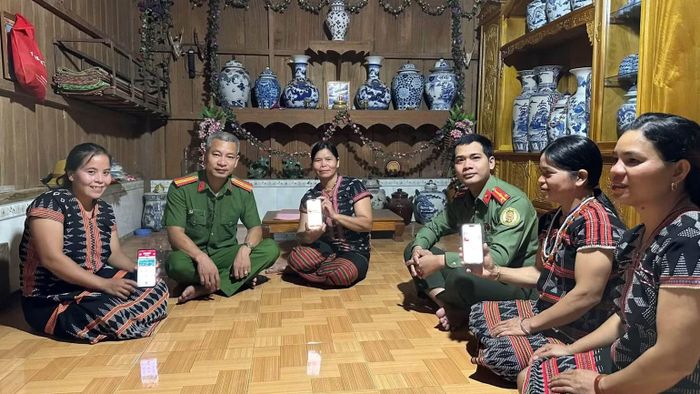 Công an xã A Vương hỗ trợ người dân cập nhật thông tin lên ứng dụng VNeID trên điện thoại. (Ảnh: HỮU KHÁNH)