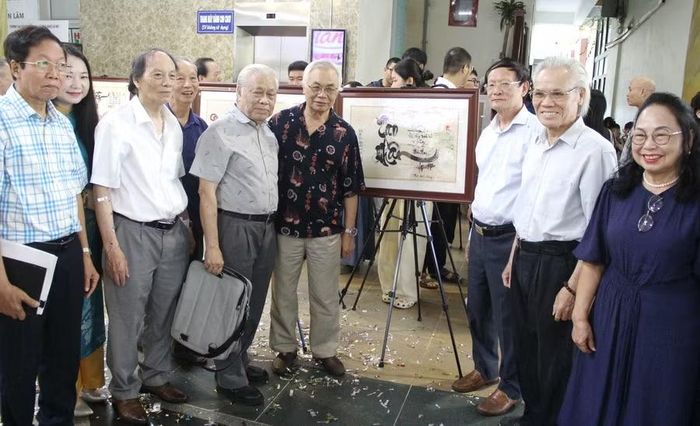 Các đại biểu chụp hình lưu niệm bên tác phẩm thơ thư pháp.