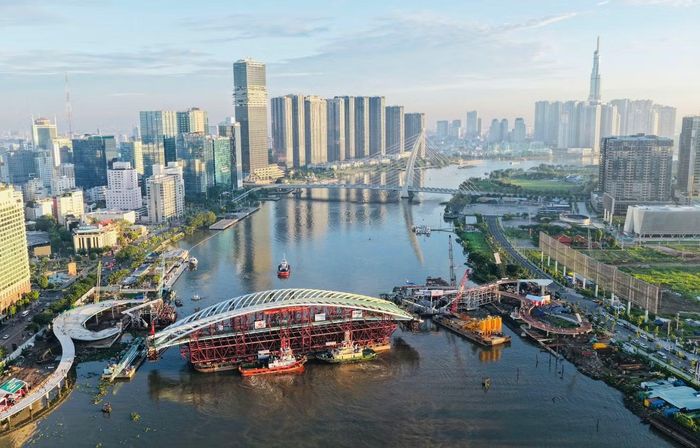 Đến 6h sáng 21/10, các đơn vị thi công đang tiếp đầu xoay, căn chỉnh sà lan chở nhịp chính cầu đi bộ hình lá dừa nước nặng 3.400 tấn trên sông Sài Gòn, chuẩn bị kết thúc cho công đoạn hợp long, kết nối các phần kết cấu của công trình.
