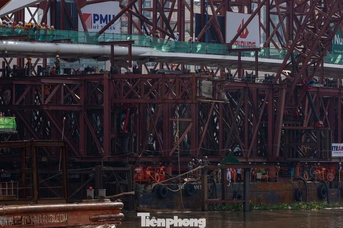 Đội ngũ công nhân phối hợp thực hiện công tác tháo dỡ hệ thống trụ dầm biên, giải phóng các liên kết của hệ giàn phân tải để chuẩn bị đưa sà lan ra khỏi khu vực thi công.