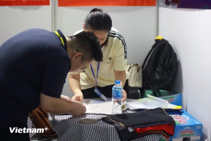 Khách tham quan trực tiếp trải nghiệm, kiểm tra chất liệu các dòng vải và nguyên phụ liệu được trưng bày tại sự kiện. (Ảnh: Đức Hiếu/Vietnam+)