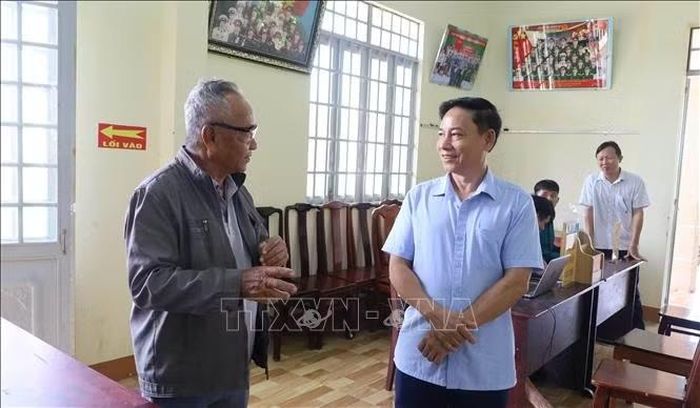 Chủ tịch UBND phường Đồng Phú Hồ Hùng Phi (phải) trao đổi với người dân về tình hình giải quyết thủ tục hành chính tại khu phố Tân Long.