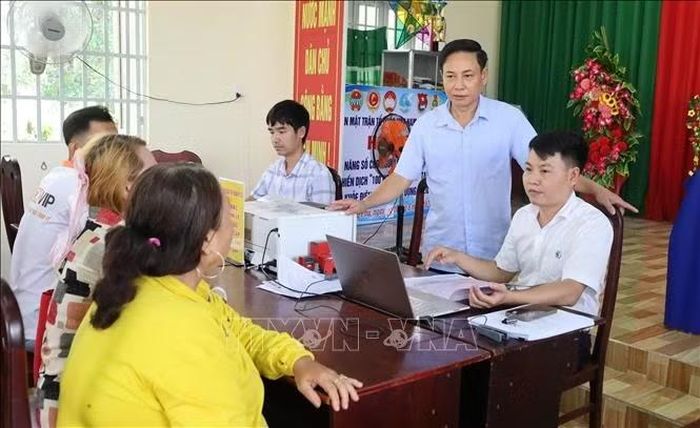 Chủ tịch UBND phường Đồng Phú Hồ Hùng Phi (đứng) trao đổi với người dân tại điểm dịch vụ công lưu động.