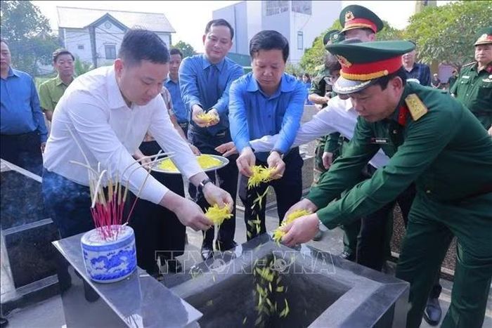 Các đại biểu thả hoa tưởng niệm liệt sĩ tại Nghĩa trang Liệt sĩ xã Sơn Lương.