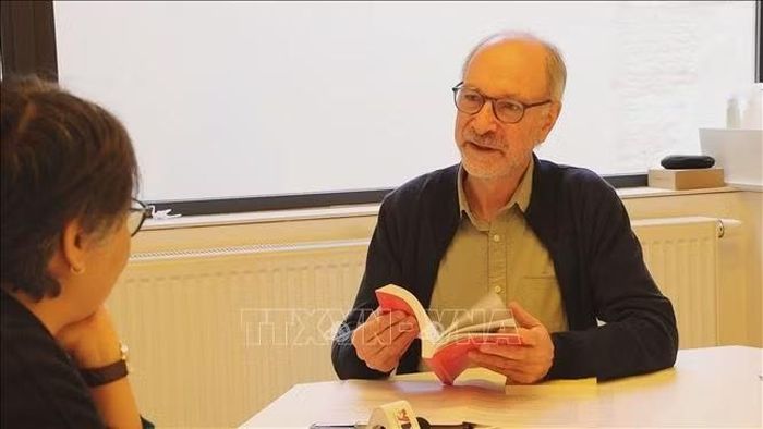 Ông Bert De Belder giới thiệu cuốn "Mutiny: How our world is tilting" (Nổi loạn: Thế giới đang nghiêng đổ như thế nào) của ông Peter Mertens. Ảnh: Duy Tùng /PV TTXVN tại Bỉ