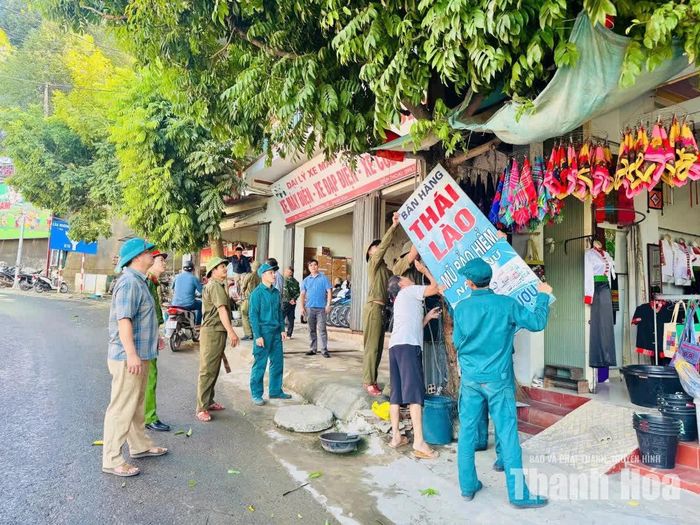 Lực lượng chức năng xã Mường Lát hỗ trợ người dân tháo dỡ biển quảng cáo lấn chiếm vỉa hè.