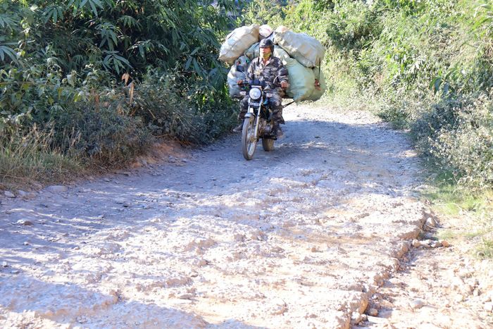 Mặt đường gồ ghề, nhiều đá sỏi gây khó khăn cho việc đi lại và vận chuyển nông sản của người dân.