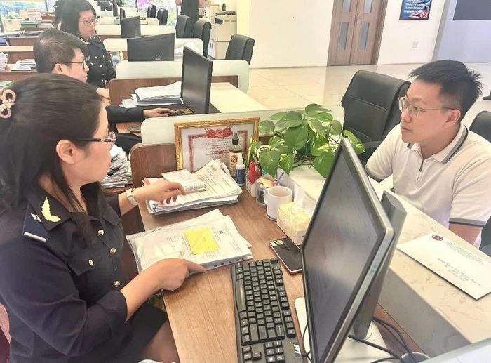 Cán bộ hải quan hỗ trợ doanh nghiệp hoàn thành thủ tục xuất nhập khẩu. Ảnh: Hải Anh