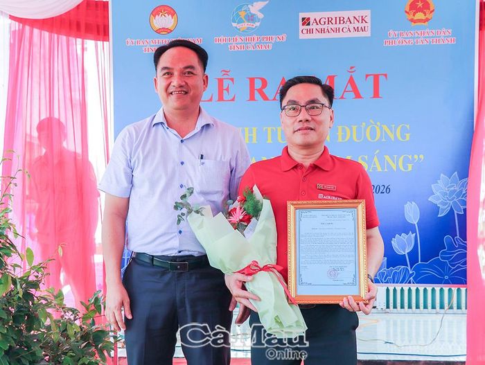 Phó Chủ tịch UBND phường Tân Thành Lâm Bảo Xuyên tặng hoa và thư cảm ơn đại diện Ngân hàng Agribank chi nhánh Cà Mau đã hỗ trợ kinh phí xây dựng mô hình tuyến đường “Ngày xanh - Đêm sáng” trên địa bàn Khóm 7.
