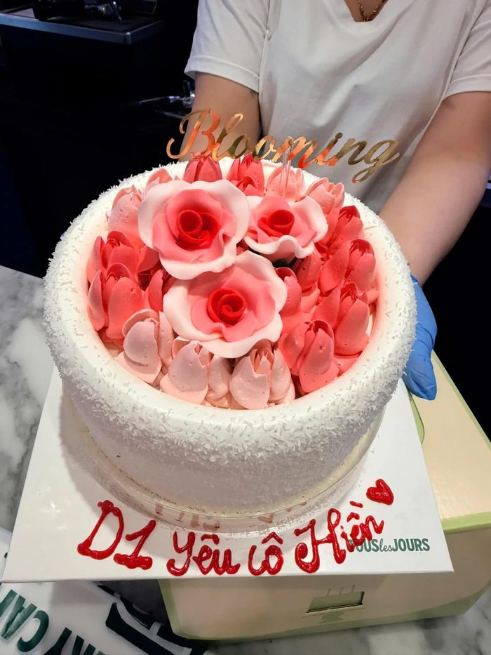 Chiếc bánh kem trang trí hoa hồng với dòng chữ “D1 yêu cô Hiền”, góp thêm nét ngọt ngào cho buổi chúc mừng.