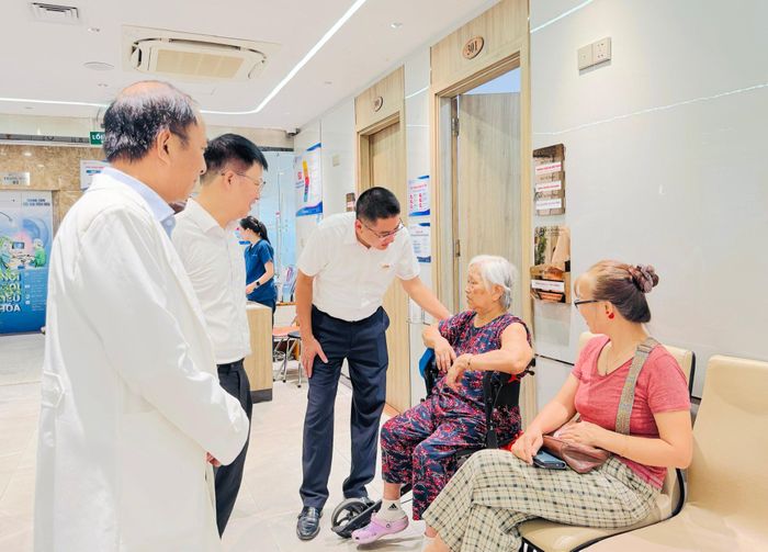 Lãnh đạo phường Kim Liên trò chuyện, động viên người cao tuổi đang thăm, khám bệnh miễn phí tập trung tại Bệnh viện Đông Đô. Ảnh: NB
