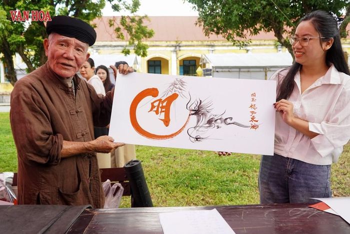 Nghệ nhân Hồ Viết Sanh (đến từ TP. Đà Nẵng) tặng tác phẩm thư pháp cho du khách. Ảnh: S.Thùy