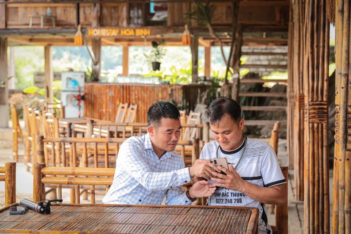 Ông Nguyễn Duy Tư, Bí thư Đảng ủy xã Vân Sơn, tỉnh Phú Thọ hướng dẫn chủ homestay sử dụng điện thoại để ghi hình, giới thiệu không gian lưu trú, các dịch vụ và những nét đặc trưng của cơ sở trên nền tảng số. Ảnh: Phạm Tuấn Anh