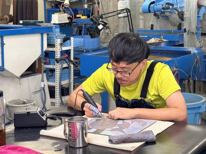 Một nghệ sĩ đang vẽ trên một tấm thủy tinh tại Viện Nghệ thuật Thủy tinh Toyama