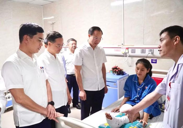 Thứ trưởng Đoàn Trung Kiên và đoàn công tác nghe bác sĩ Bệnh viện Đa khoa Cửa Đông thông tin về phác đồ điều trị, phục hồi chức năng cho cô giáo Hoàng Thị Hiền. Ảnh: Hồ Lài