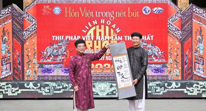 TS Lê Ngọc Dũng, Chủ tịch Hội Nghệ nhân và Thương hiệu Việt Nam (trái) trao tặng bức thư pháp cho ông Hoàng Việt Trung, Giám đốc Trung tâm Bảo tồn Di tích Cố đô Huế.