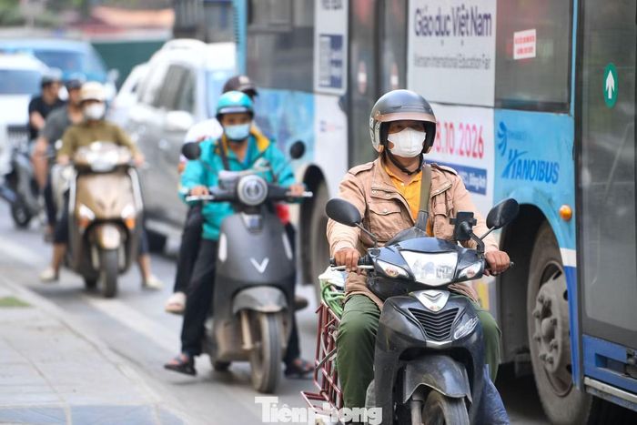 Mặt đường thu hẹp, xe máy và các phương tiện khác di chuyển chậm sát hàng rào tôn công trường.