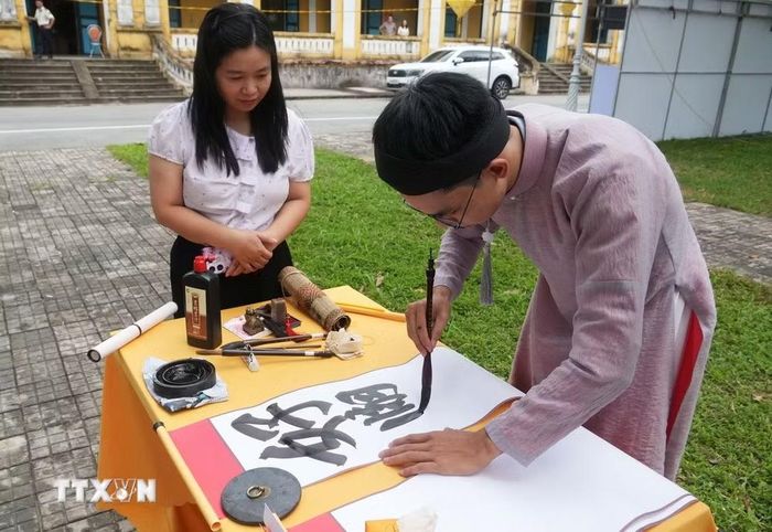 Du khách xem trình diễn thư pháp tại Liên hoan Thư pháp Việt Nam lần thứ nhất năm 2026. (Ảnh: Nguyên Lý/TTXVN)