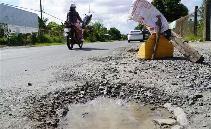 Người dân đặt vật dụng cảnh báo người lái xe né tránh các ổ gà, ổ voi trên Quốc lộ 80.