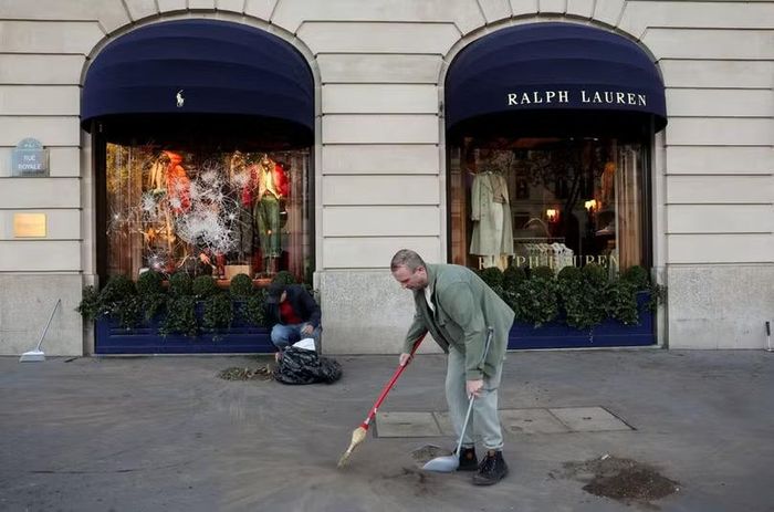 Công tác dọn dẹp diễn ra bên ngoài một cửa hàng Ralph Lauren bị hư hại ở Paris, ngày 18/10. Ảnh: Reuters.