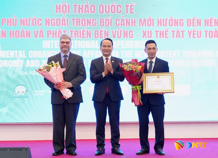 Phó Bí thư Thành ủy, Chủ tịch Ủy ban MTTQ Việt Nam thành phố Nguyễn Đình Vĩnh (giữa) tặng bằng khen của UBND thành phố cho đại diện tổ chức Catalyste+ (Canada). Ảnh: T.CÔNG