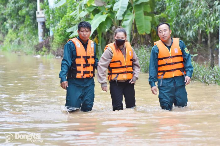 Phường Phước Tân bố trí lực lượng tại một số điểm ngập sâu, giăng dây cảnh báo, hỗ trợ người dân đi qua dòng nước xiết. Ảnh: LA